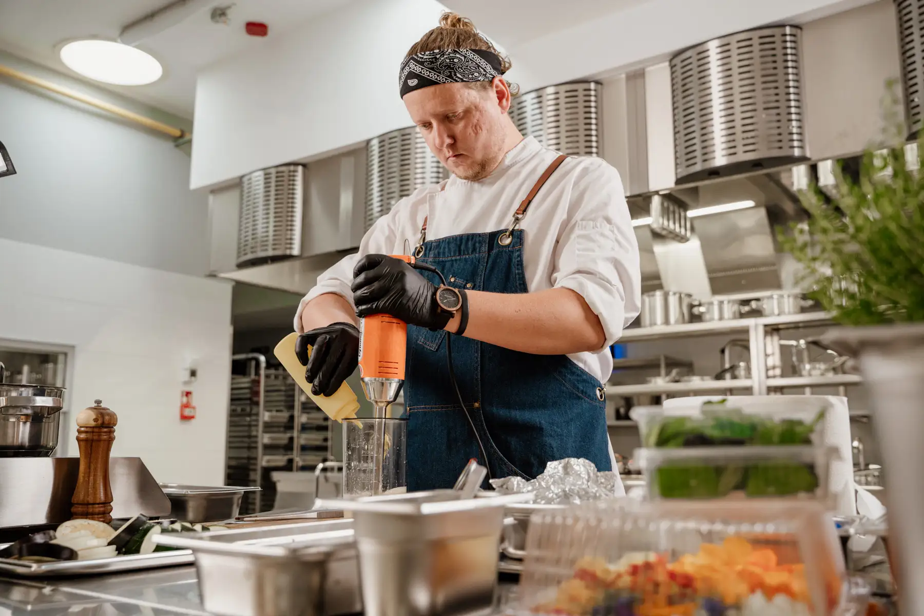 Kucharz Tomasz Rymisz przygotowujący potrawę blenderem ręcznym Dynamic w profesjonalnej kuchni gastronomicznej.